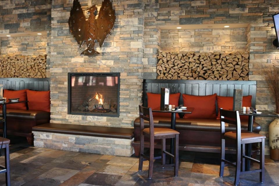 Morrisville-NC-cozy-restaurant-interior-displaying-a-fireplace-centered-around-custom-made-wood-booths-and-bar-stools
