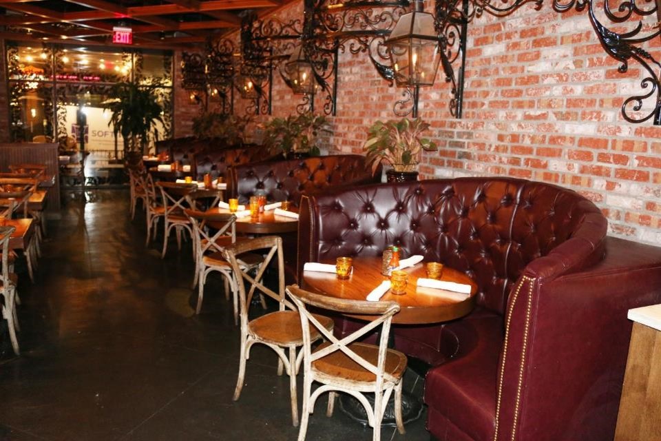 Oxen-Hill-MD-moody-restaurant-interior-with-curved-dark-red-tufted-leather-booths-lined-along-brick-wall-with-candles-lit