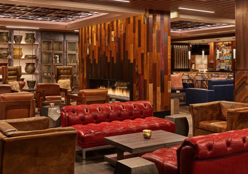 Snowmass-Village-CO-aerial-view-of-lounge-interior-with-custom-built-red-leather-tufted-benches-and-brown-leather-seats-centered-around-wood-coffee-table-fireplace-in-background